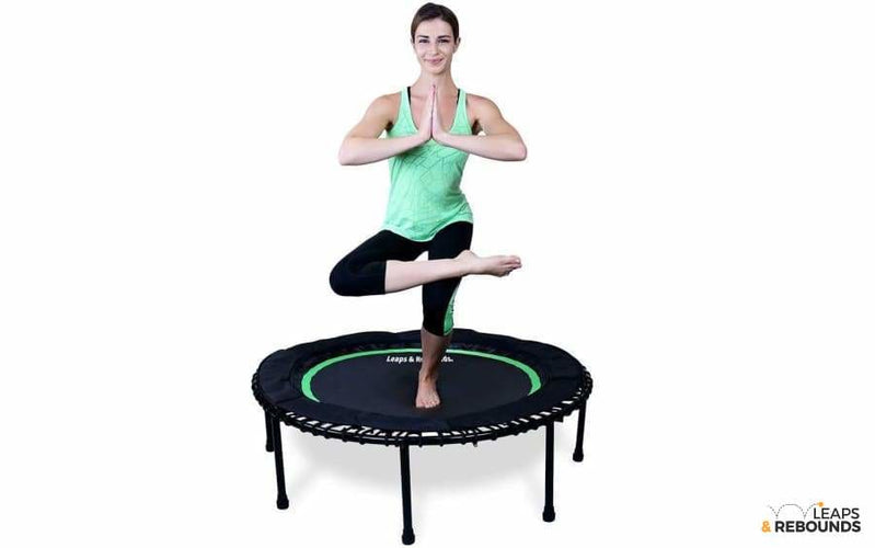 Model balancing on top of green mini trampoline