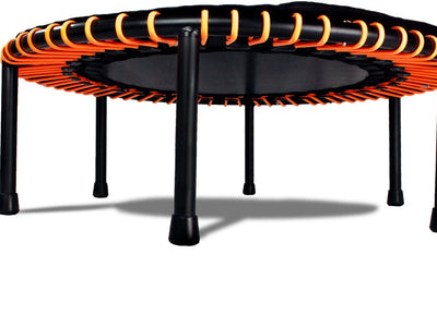 Small round trampoline with orange bands and black legs, isolated.