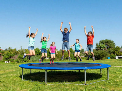 Children jumping on a large outdoor trampoline.