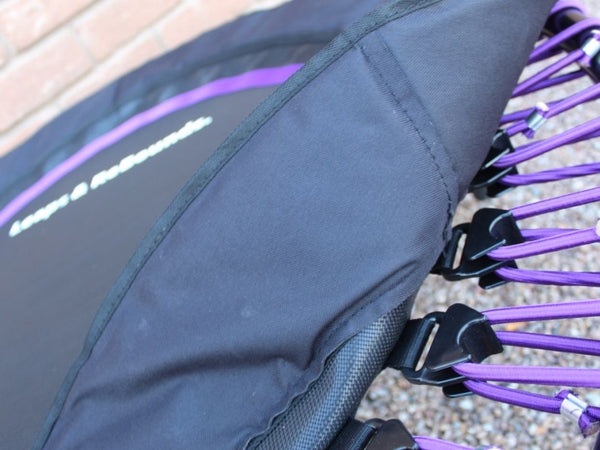 Close-up of a mini trampoline with purple bungee cords.