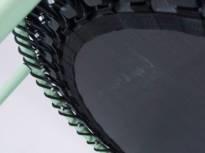 Close-up of a mini trampoline with green frame and cords.