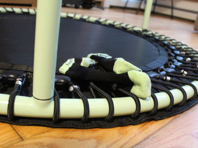 Small trampoline with green frame and socks on top.