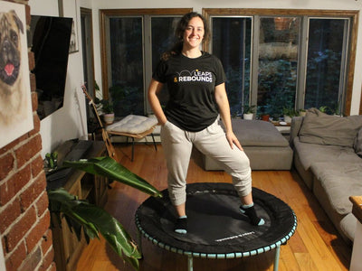 Person standing on mini trampoline in cozy living room setting.