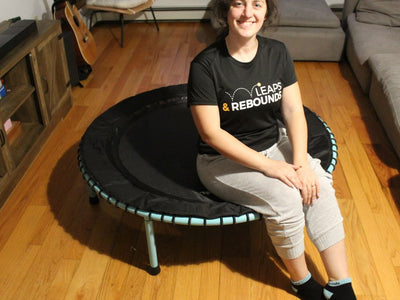 Person sitting on a mini trampoline in a cozy living room.