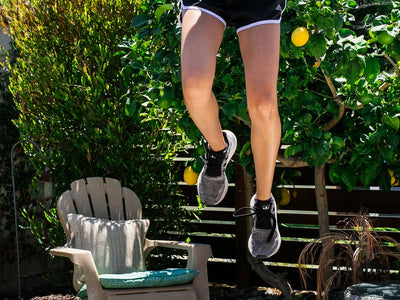 Person jumping on a trampoline in a sunny backyard setting.