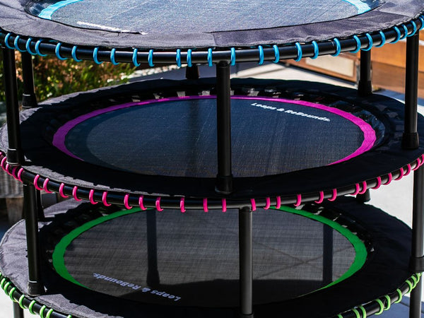 Three mini trampolines stacked outdoors on a sunny patio.