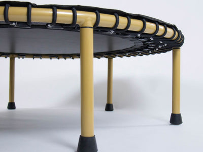 Close-up of a mini trampoline with yellow legs and black mat.