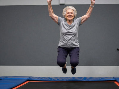 Elderly woman joyfully jumping on a trampoline.