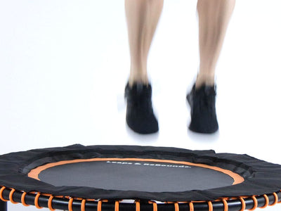 Person jumping on a small trampoline with orange accents.