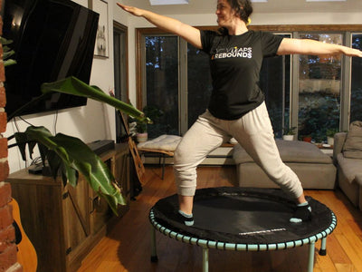 Person doing yoga pose on trampoline in cozy living room.