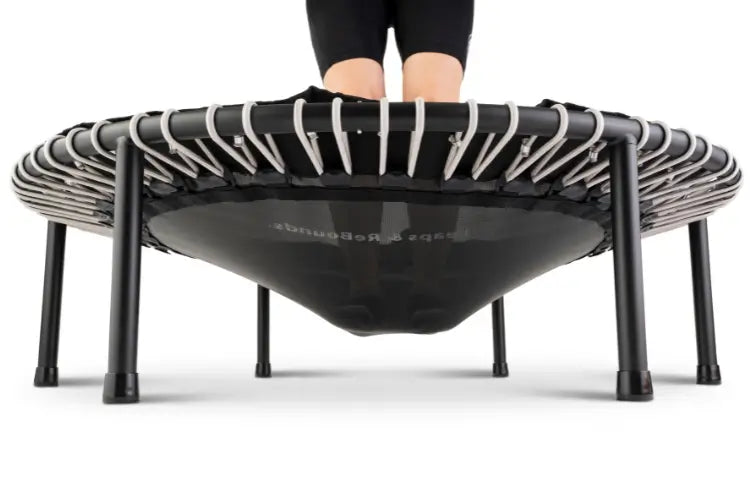 Person using a black and white Leaps and Rebounds fitness rebounder on a white background
