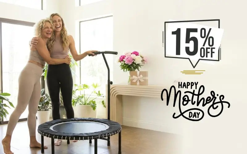 Two women playing with a trampoline in a home setting, with a Mother's Day sale promotion on the wall.