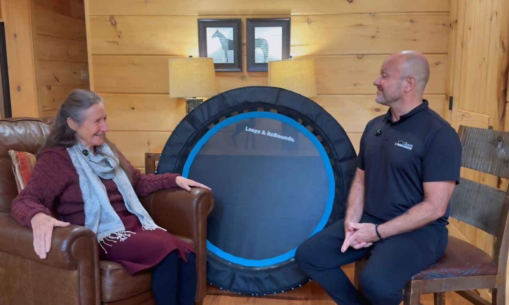 Barbara O'Neill seated in a cabin with a Leaps and Rebounds representative, the 40-inch bungee rebounder between them.